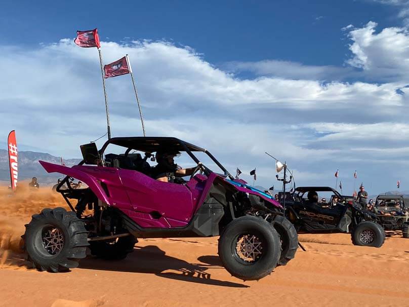 Profile shot of two Yamaha YXZ drag racing in the sand.